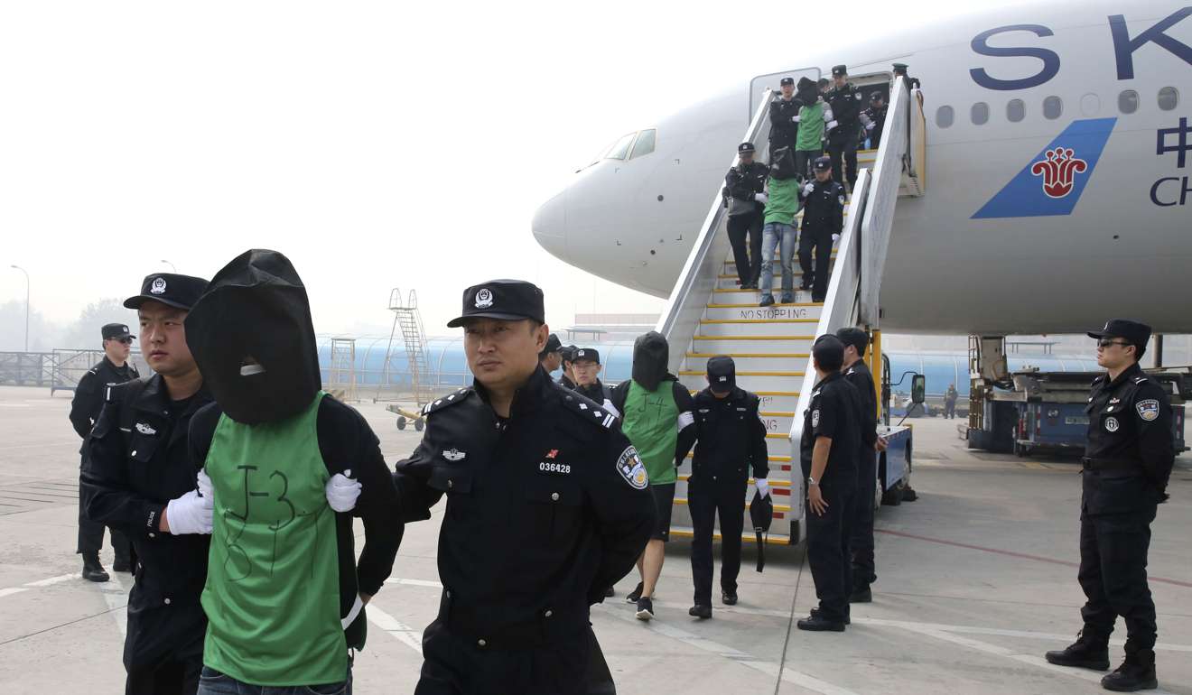 Mainland Chinese and Taiwanese suspects involved in wire fraud are escorted off a plane upon arriving at the Beijing Capital International Airport in Beijing in April last year. Photo: AP