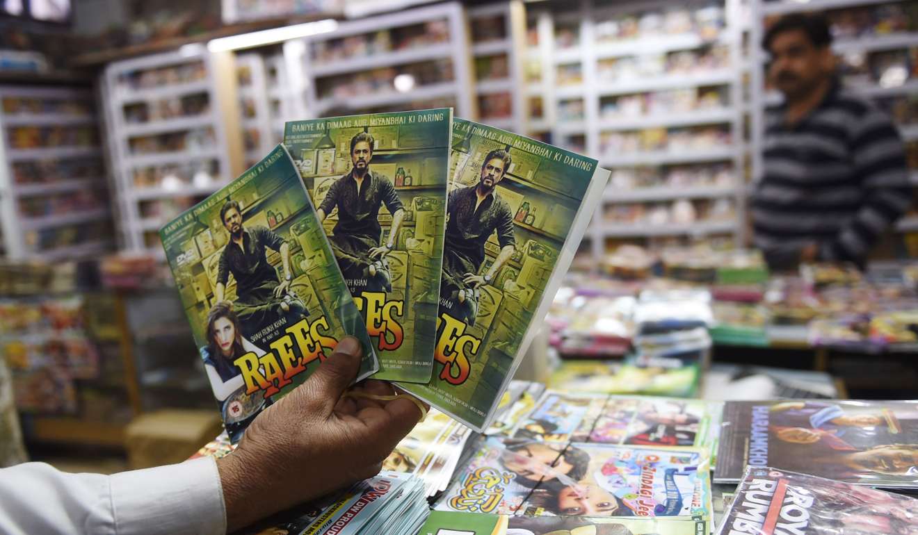 A Pakistani vendor poses for a photograph with pirated copies of Indian Bollywood film Raees at his shop in Karachi. Photo: AFP