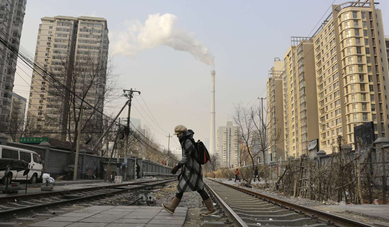 A woman crosses a railway line near a heating plant in Beijing. Photo: Reuters
