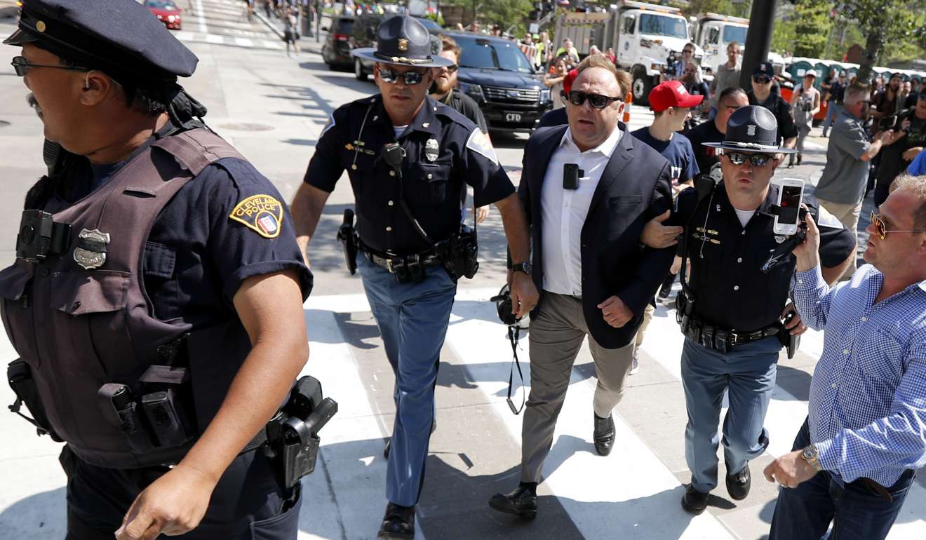 Alex Jones, centre right, is escorted by police out of a crowd of protesters outside the Republican convention in Cleveland on July 19. 2016. Photo: AP
