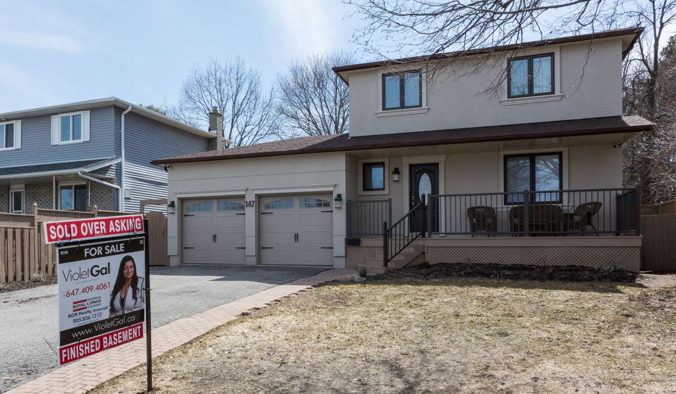 A placard reading ‘Sold Over Asking’ is seen on top of a real estate sign displayed outside a home in Barrie, Ontario. Photo: Bloomberg