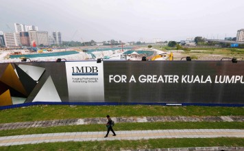 A man walks past a 1MDB billboard at the funds flagship Tun Razak Exchange development in Kuala Lumpur, last year. Photo: Reuters