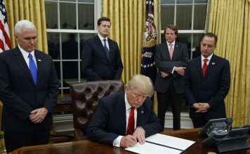 In this January 20 photo, US President Donald Trump, flanked by Vice President Mike Pence (left) and Chief of Staff Reince Priebus (right), signs his first executive order on health care in the Oval Office of the White House in Washington. Photo: AP
