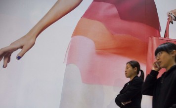 People walk past an advertising hoarding outside a Fendi luxury leather goods store, in Hong Kong.