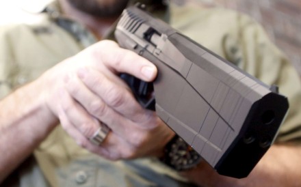 A man holding a Maxim 9 handgun, which has a built-in silencer. Photo: Reuters