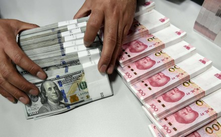 A clerk counts Chinese yuan and US dollar banknotes at a bank in China. Photo: Reuters