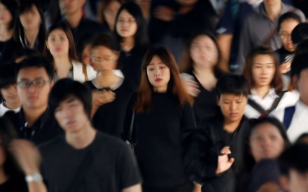 Commuters dressed in black and white or dark coloured clothes, to mourn the passing of Thailand's King Bhumibol Adulyadej, head to work during morning rush hour in Bangkok Monday. Photo: Reuters