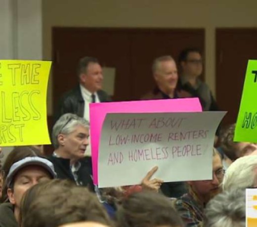 People hold up signs at a March 16 "emergency meeting" on affordable housing in Vancouver. Local MLA David Eby told the meeting that "extreme wealth" should not put anyone at the front of an immigration queue. Photo: CBC People hold up signs at a March 16 "emergency meeting" on affordable housing in Vancouver. Local MLA David Eby told the meeting that "extreme wealth" should not put anyone at the front of an immigration queue. Photo: CBC