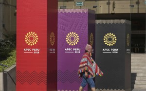 A man dressed in traditional Andean clothes walks past the logo of the APEC 2016 summit in Lima, Peru. Photo: AP