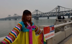 A Chinese woman poses in Korean clothing as trucks carrying Chinese-made goods cross into North Korea on the Sino-Korean Friendship Bridge at the border town of Dandong. Chinese tourism to North Korea is on the increase. Photo: AFP A Chinese woman poses in Korean clothing as trucks carrying Chinese-made goods cross into North Korea on the Sino-Korean Friendship Bridge at the border town of Dandong. Chinese tourism to North Korea is on the increase. Photo: AFP