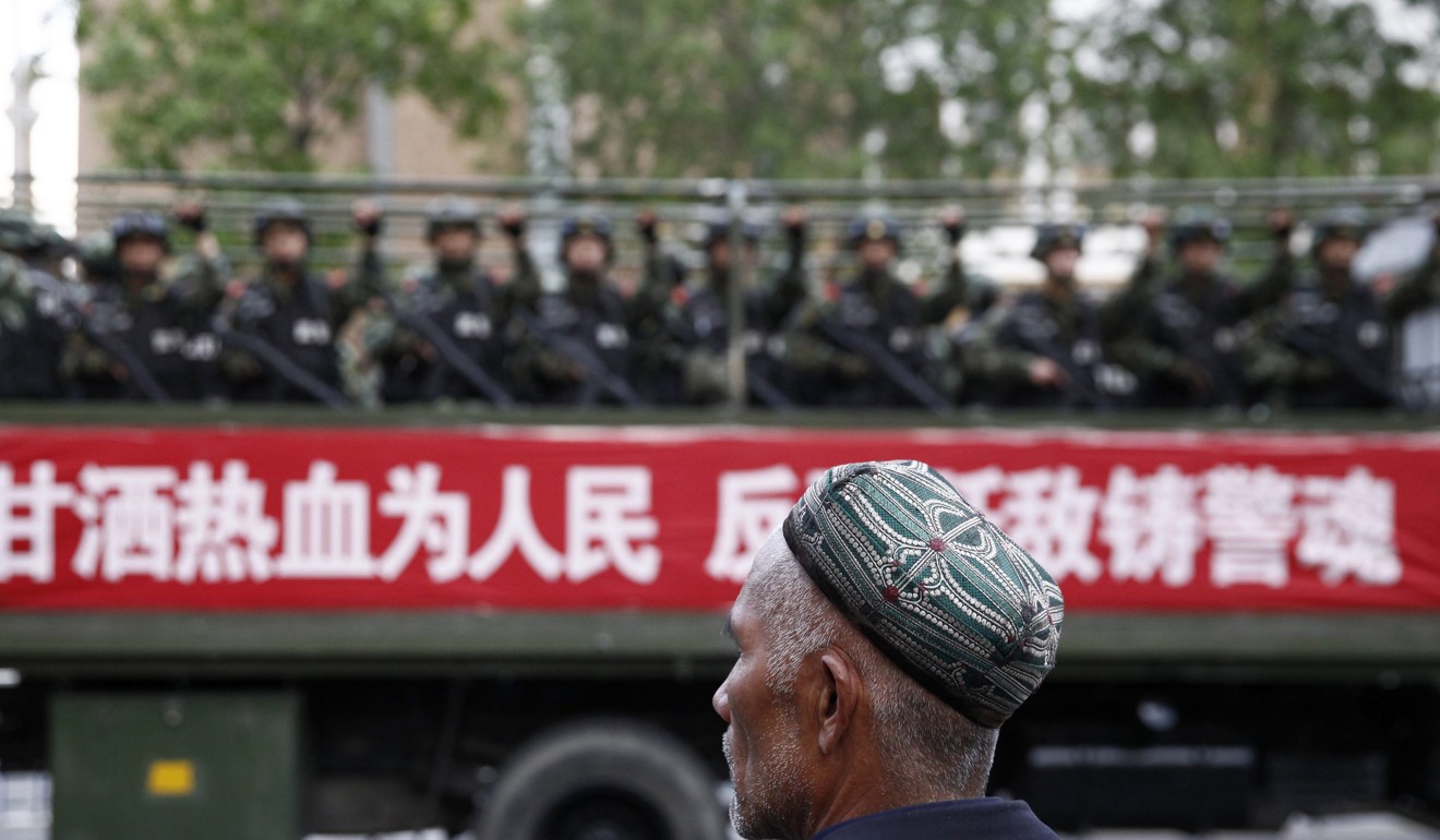 A Uygur man looks on as a truck carrying paramilitary police in Urumqi, Xinjiang in May 2014. Photo: Reuters