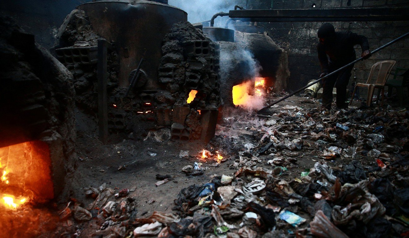 A man works in a workshop in the rebel-held besieged Douma neighbourhood of Damascus, Syria, last month. The workshop uses plastic from bottles and other waste materials to produce liquid and gas fuels. Syria is in the grip of a civil war and various Jihadist groups have seized on the divisions. Photo: Reuters