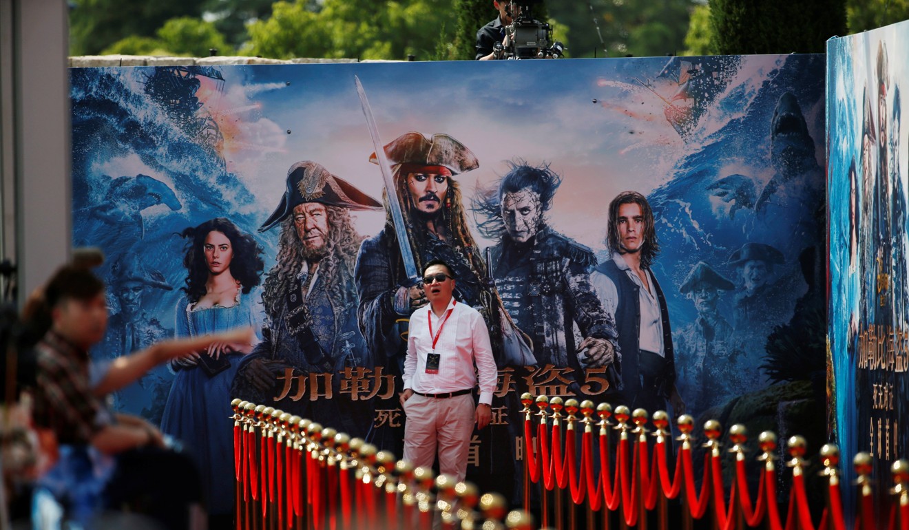 A staff member stands in front of a poster advertising the launch of Pirates of the Caribbean: Dead Men Tell No Tales in Shanghai. Photo: Reuters