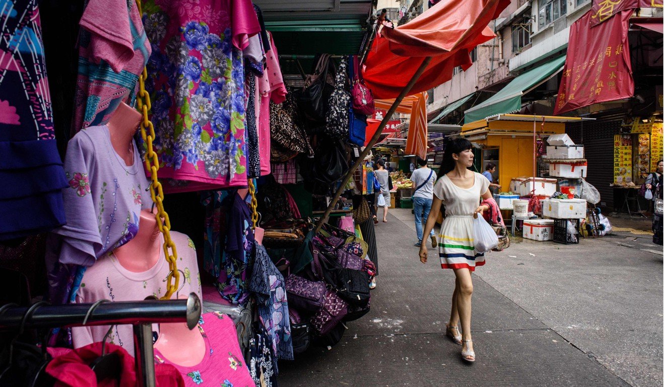 A woman walks past a display of clothes at a street market stall in Hong Kong. Many families in Hong Kong rely heavily on foreign domestic workers to look after babies and grandparents while both husbands and wives go to work. Photo: AFP