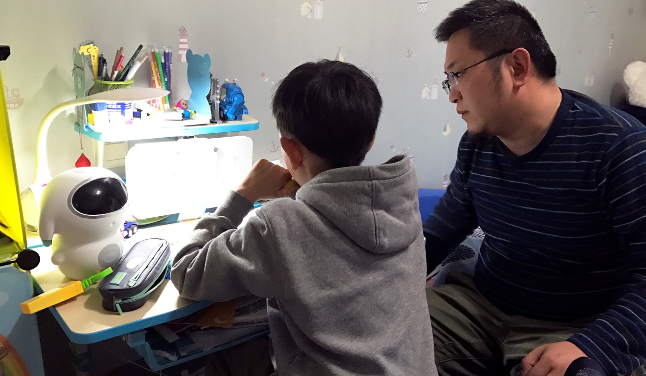 8-year-old Hu Yizhuo does his homework with his father Hu Chengyu in Nanjing, Jiangsu province. Photo: Reuters