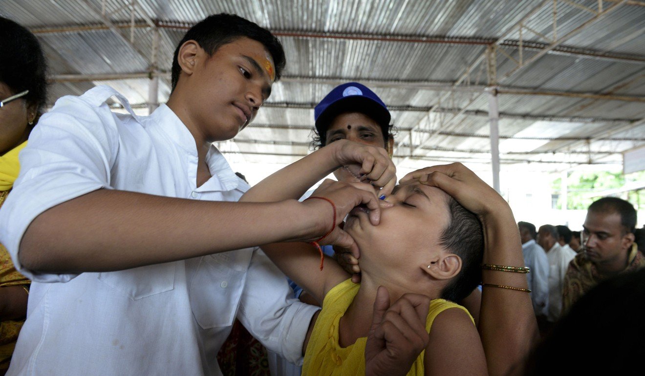 A member of the Bathini Goud family administers the 'fish medicine' to a young girl at the exhibition grounds in Hyderabad. Photo: AFP