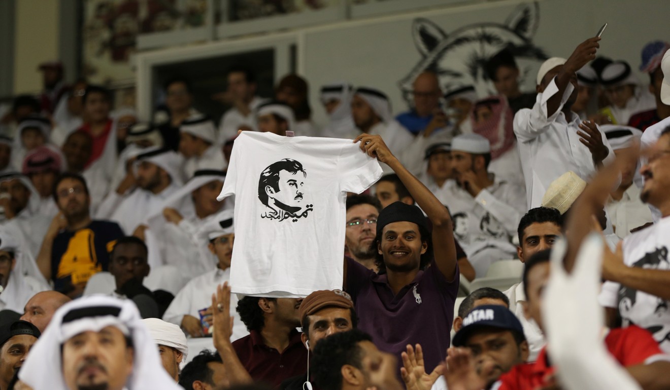 A man holds a T-shirt with a picture depicting Qatar’s Emir Sheikh Tamim Bin Hamad Al-Thani . The t-shirts read: 