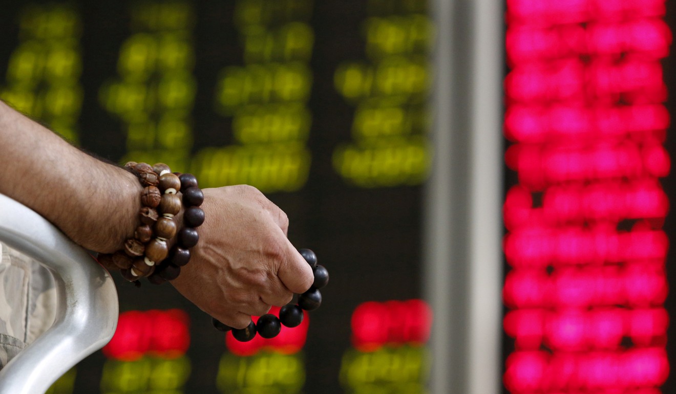 An investor holds onto prayer beads at a brokerage in Beijing. Photo: Reuters
