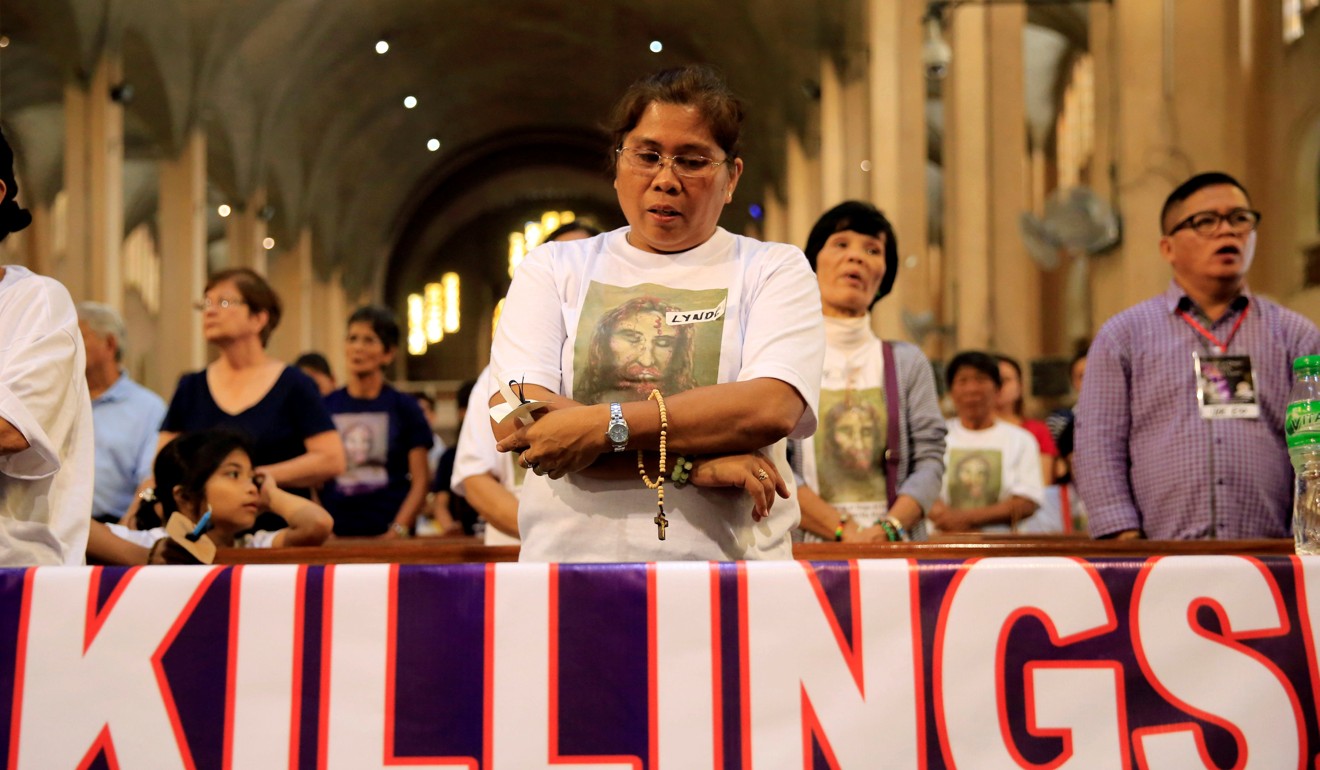 A woman prays for her loved one who she says was killed due to alleged involvement in illegal drugs, inside a Roman Catholic church. Photo: Reuters