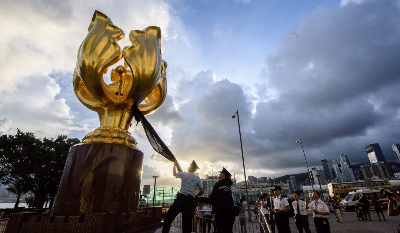 Police remove black cloth from the Golden Bauhinia statue. Photo: AFP