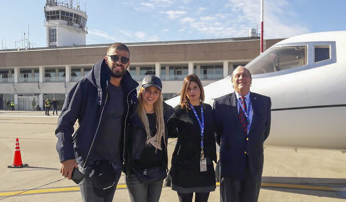 Gerard Pique (L) and his wife, Colombian singer Shakira pose with airport staff upon their arrival in Rosario. Photo: AFP