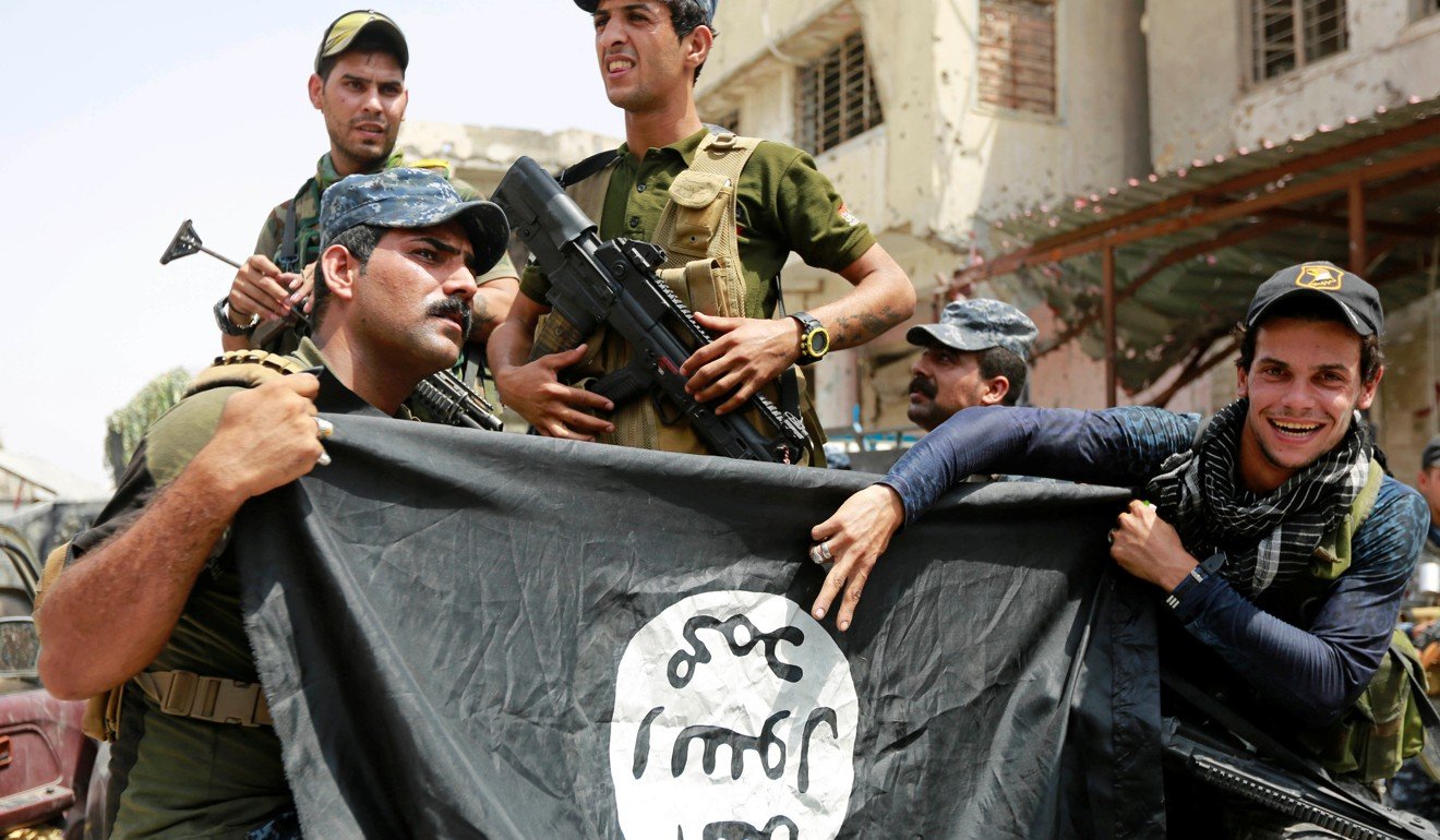 Iraqi Federal Police members hold an Islamic State flag which they pulled down during fighting between Iraqi forces and Islamic State militants, in the Old City of Mosul, Iraq, on July 4, 2017. Photo: Reuters
