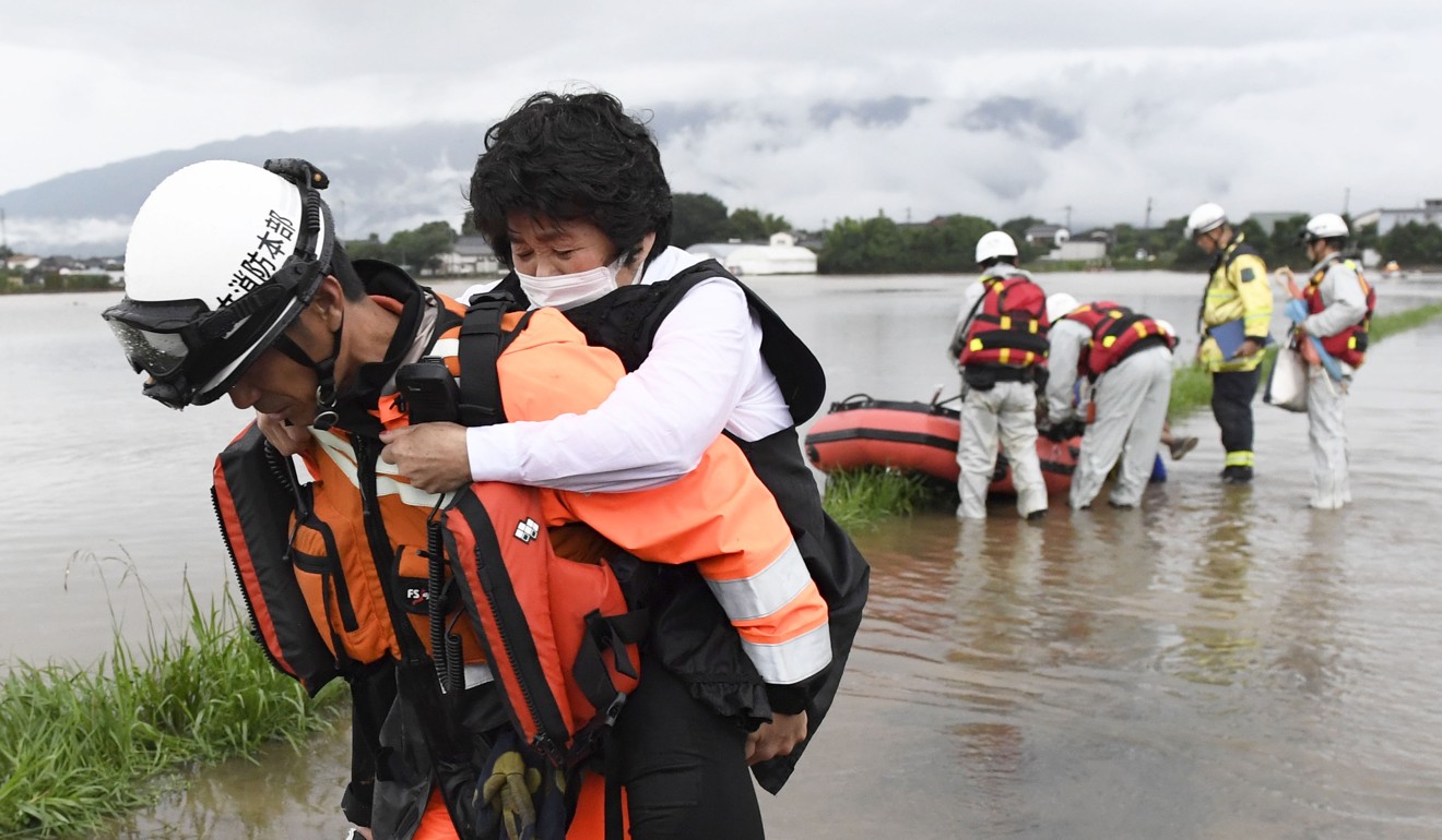 A firefighter carrying a woman who was rescued by boat in Asakura. Photo: Kyodo