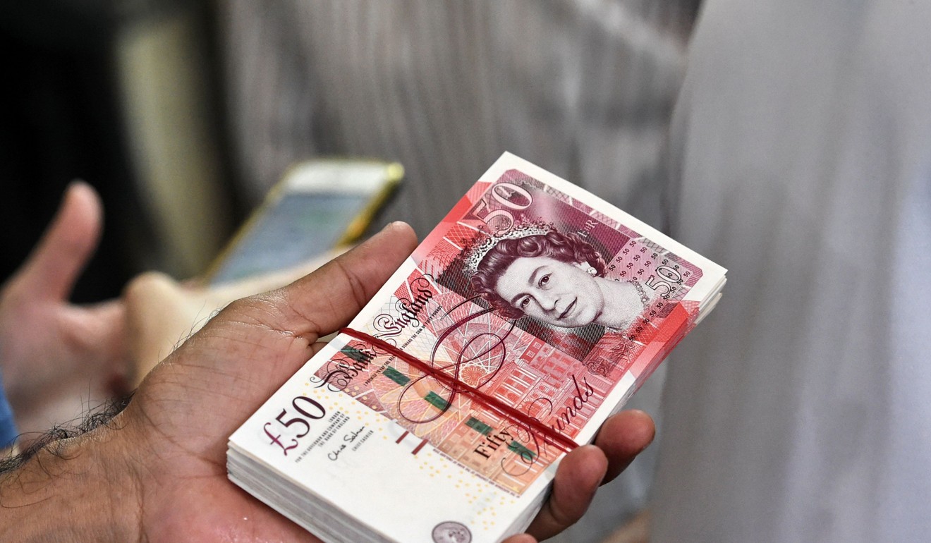 A dealer holds a stacks of British pound at a money changer booth in Singapore. Photo: AFP