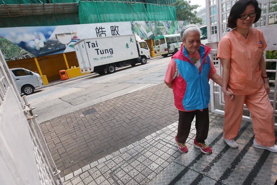 A nurse takes Au Fung-chun, 85, for a walk with a GPS vest on in Ho Man Tin. Tung Wah Group of Hospitals (TWGH) and Polytechnic University professor are creating innovative products catered to the elderly care market. Photo: SCMP/David Wong