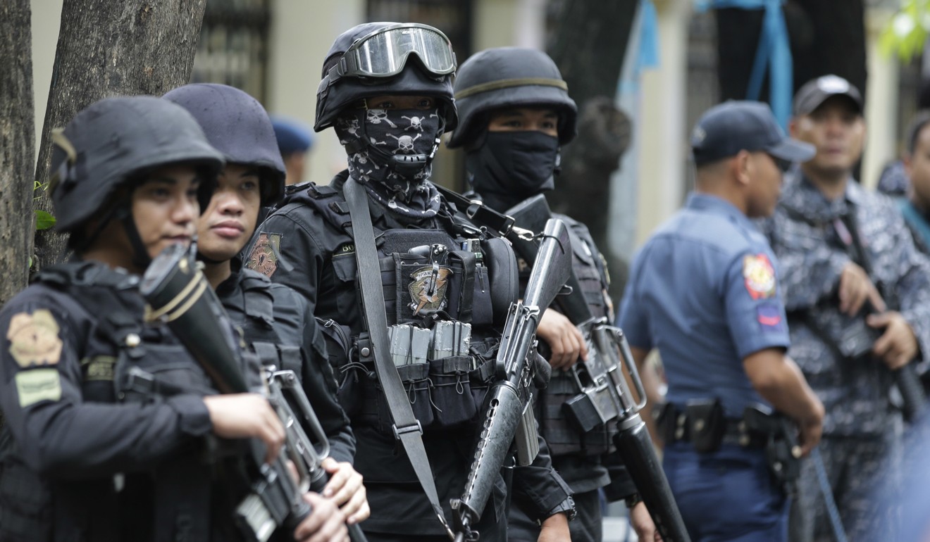 Armed police keep watch as men suspected of being en route to reinforce Marawi militants arrive at the Department of Justice in Manila. Photo: AP