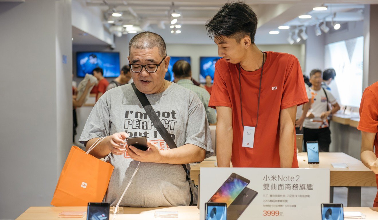 An employee assists a customer as he looks at a Xiaomi Mi Note 2 smartphone inside one of the company's stores in Hong Kong. Photo: Bloomberg