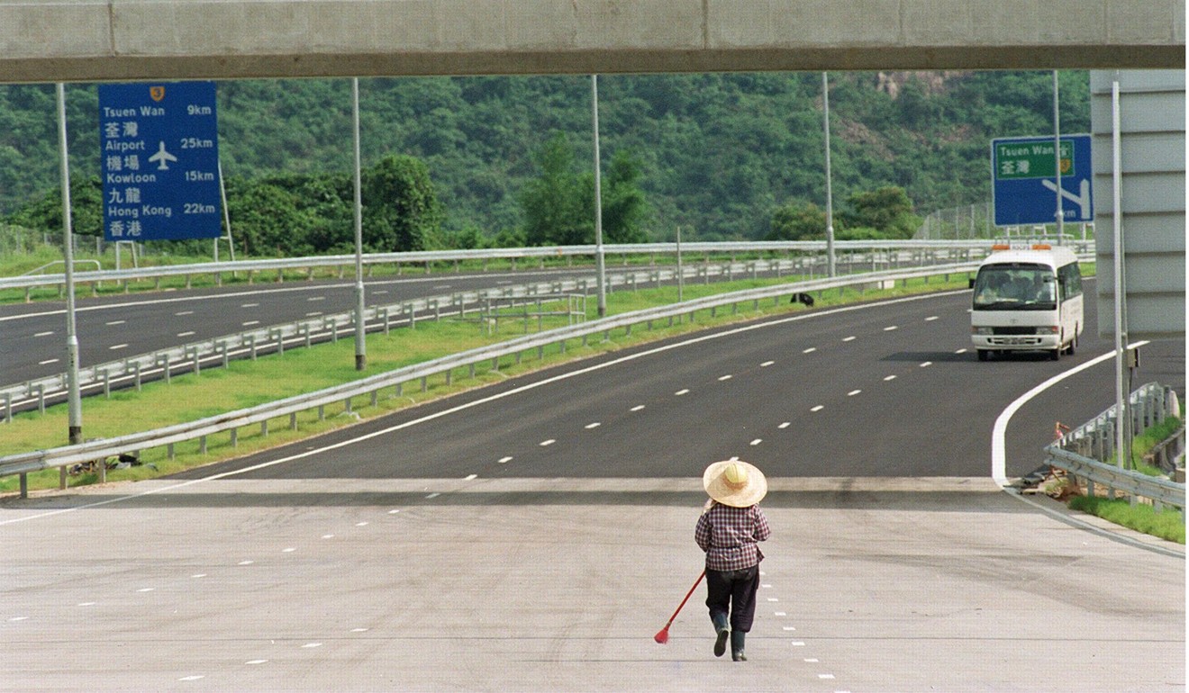 A worker cleans the road in front of toll booths on Route 3, near Tai Lam Tunnel, in preparation for its opening in 1998. To build Route 3 to Yuen Long through Tai Lam Country Park, Hong Kong limited the damage by building a tunnel instead of digging a road. Photo: Dickson Lee