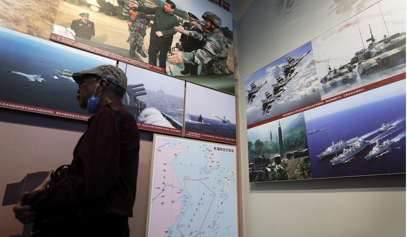 A man walks by photos showing Chinese military activities in the East China Sea in a military museum in Beijing in July. China claims indisputable sovereignty over the South China Sea islands and has built features on them. Photo: AP