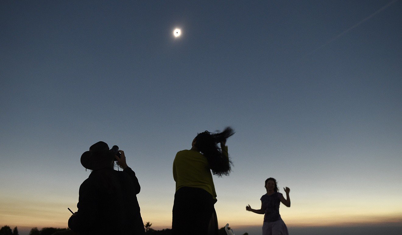Julian Ledger, of Los Angeles, photographs the solar eclipse while his wife Shayde Ledger and friend Annemarie Penny, right dance during totality at the Albany Regional Airport in Albany, Oregon, on Monday, Aug. 21, 2017. (Photo: Albany Democrat-Herald via AP