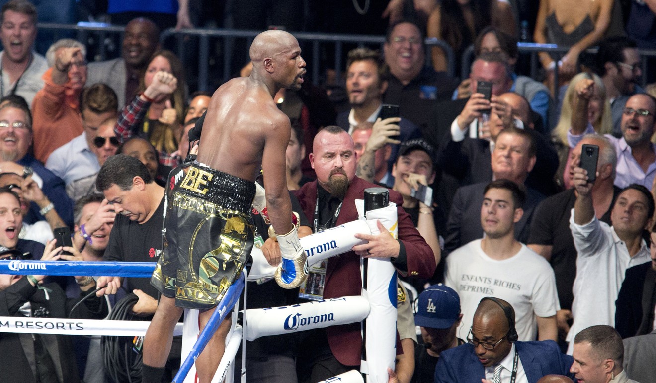 Floyd Mayweather climbs the ring ropes to celebrate his win against Conor McGregor. Photo: EPA