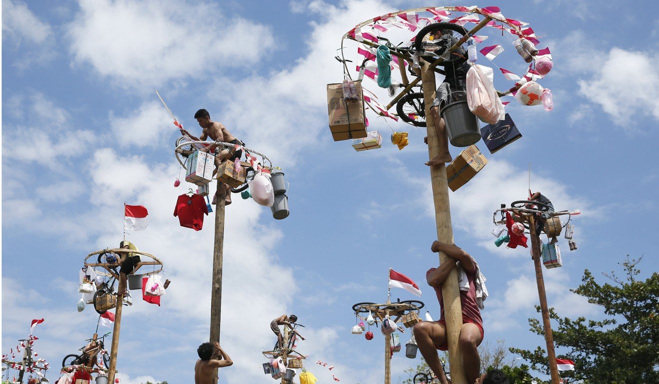Indonesians climb greased poles to collect presents during celebrations to mark the 72nd anniversary of Indonesia's independence in Denpasar, Bali. Photo: EPA