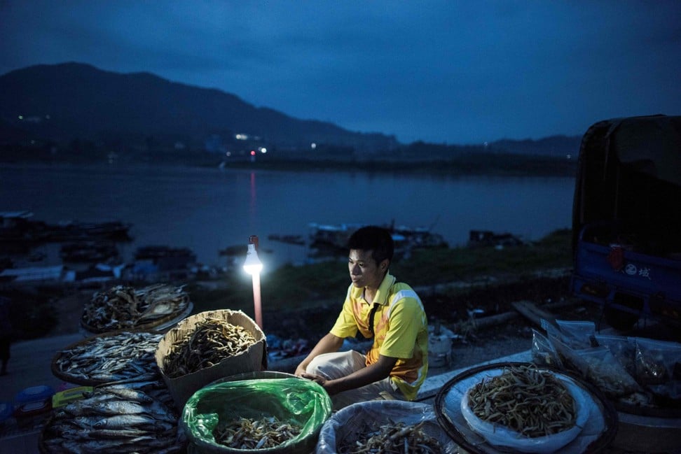 A man sells dried fish on the shore next to moored boats from the Tanka community in Datang. Photo: AFP