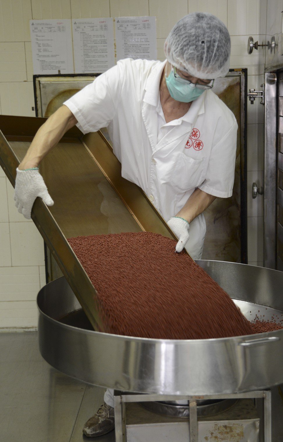 A worker pours out a tray of pills. Photo: Po Chai Pills