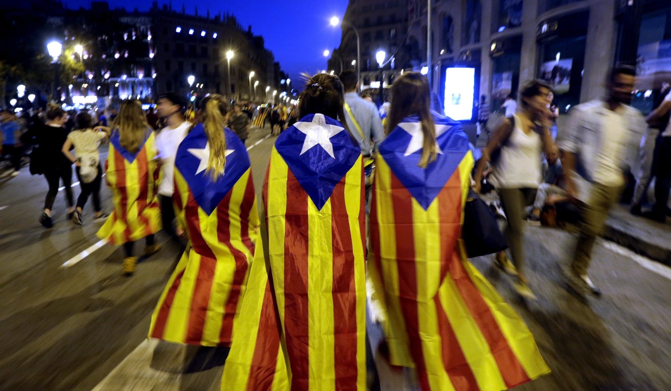 Catalan people wearing pro-independence regional flags leave after taking part in a protest at the Barcelona University's square against the Spanish police brutality on Tuesday. Photo: EPA