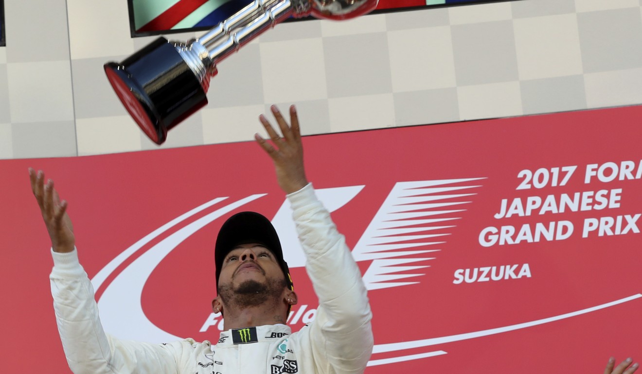 Lewis Hamilton toys with his trophy.