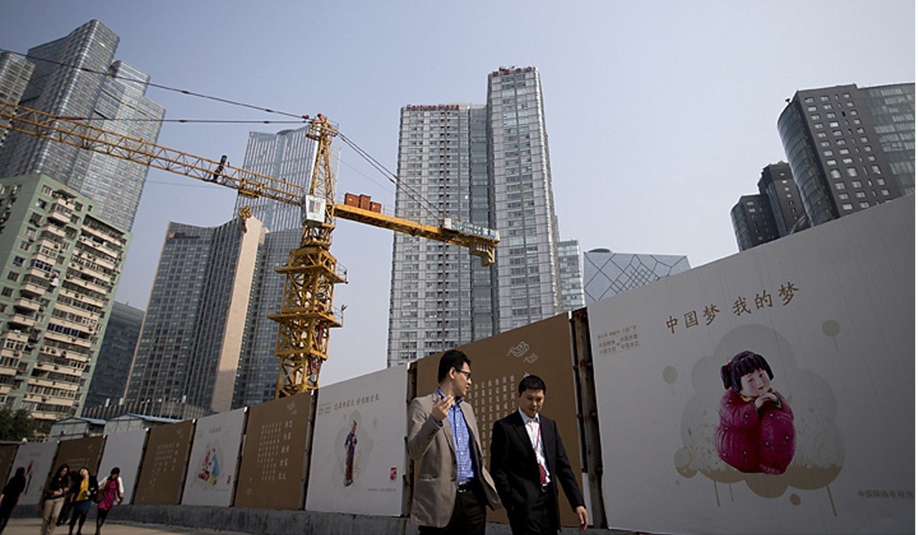 Office workers walk past propaganda posters extolling the ‘Chinese dream” near a construction site in Beijing in October 2013. Photo: AP
