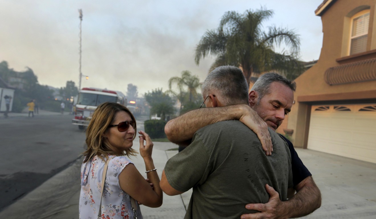 Homeowners embrace after learning their home was destroyed by the fires in Anaheim Hills, California. Photo: EPA