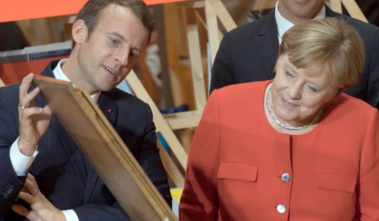 German Chancellor Angela Merkel and French President Emmanuel Macron look at the print of the declaration of Human Rights on a replica of the Gutenberg press in Germany. Photo: DPA via AFP