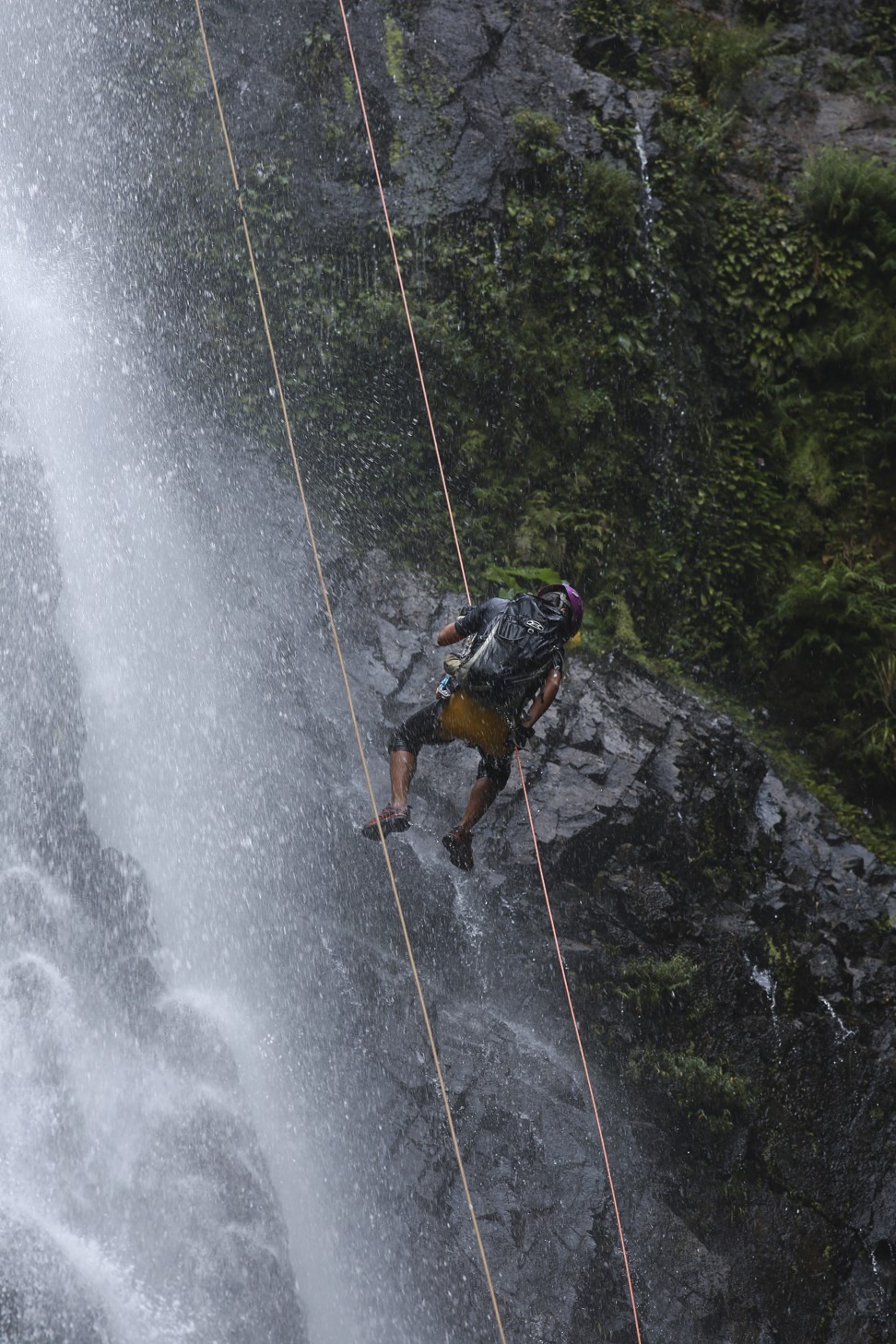 Yu abseils through the spray of a waterfall. Photo: James Wendlinger