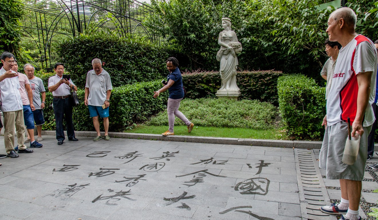People admire the work of a calligrapher (right in red and white T-shirt) in Fuxing Park.