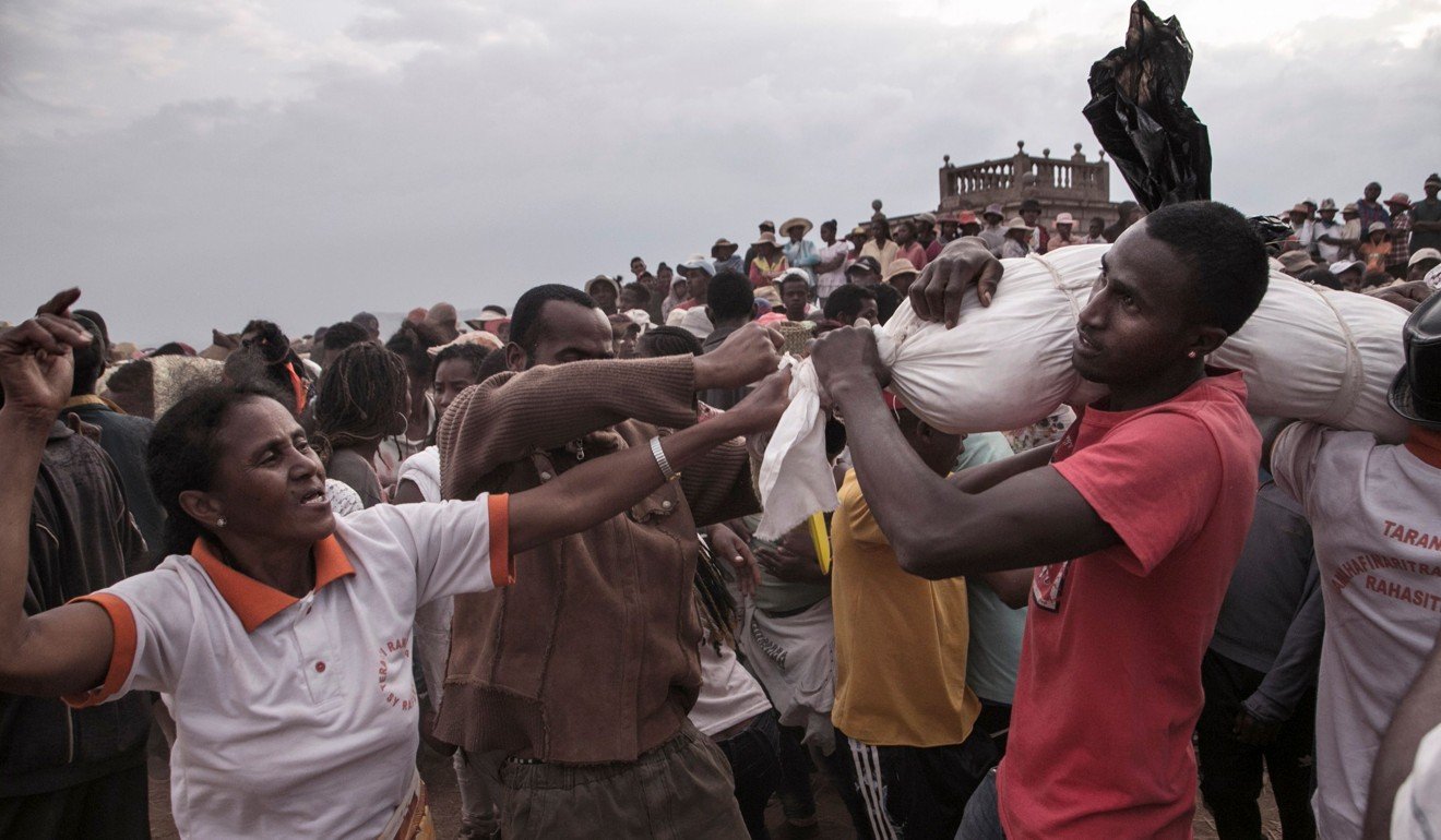 People dance and sing next to men carrying a body. Photo: AFP
