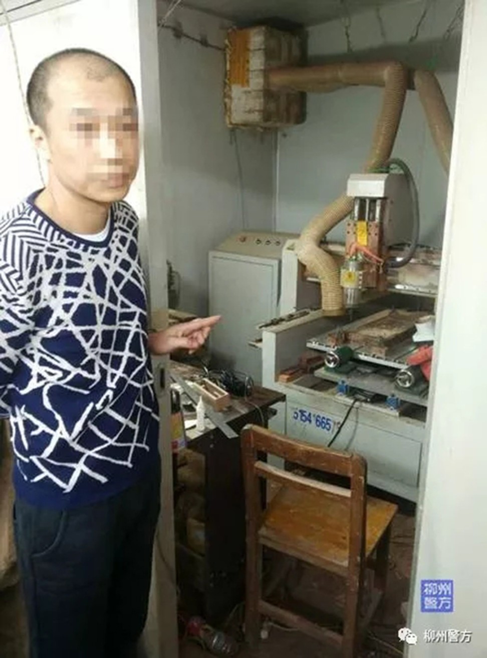 A suspect stands next to a piece of machinery that is believed to have been used to manufacture gun parts. Photo: Thepaper.cn