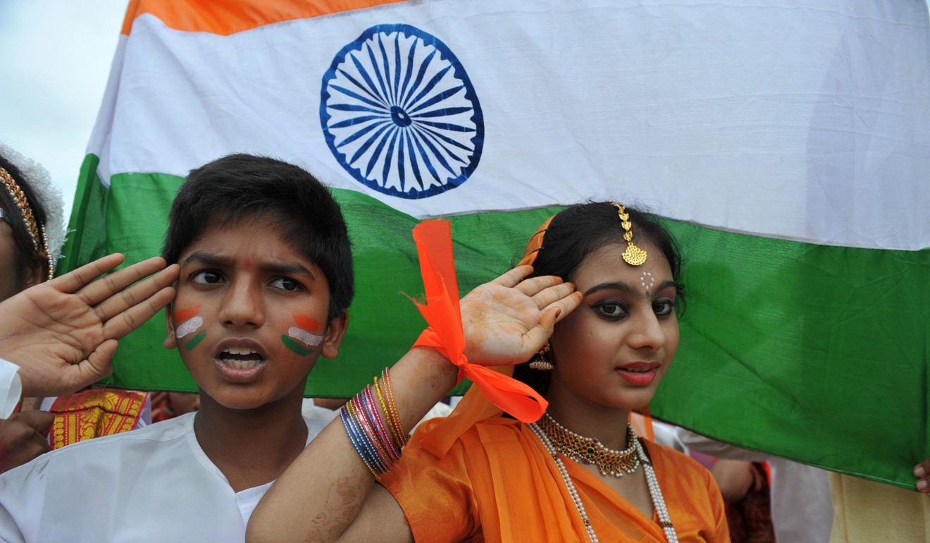 Indian school children salute as they stand to attention and sing the national anthem 