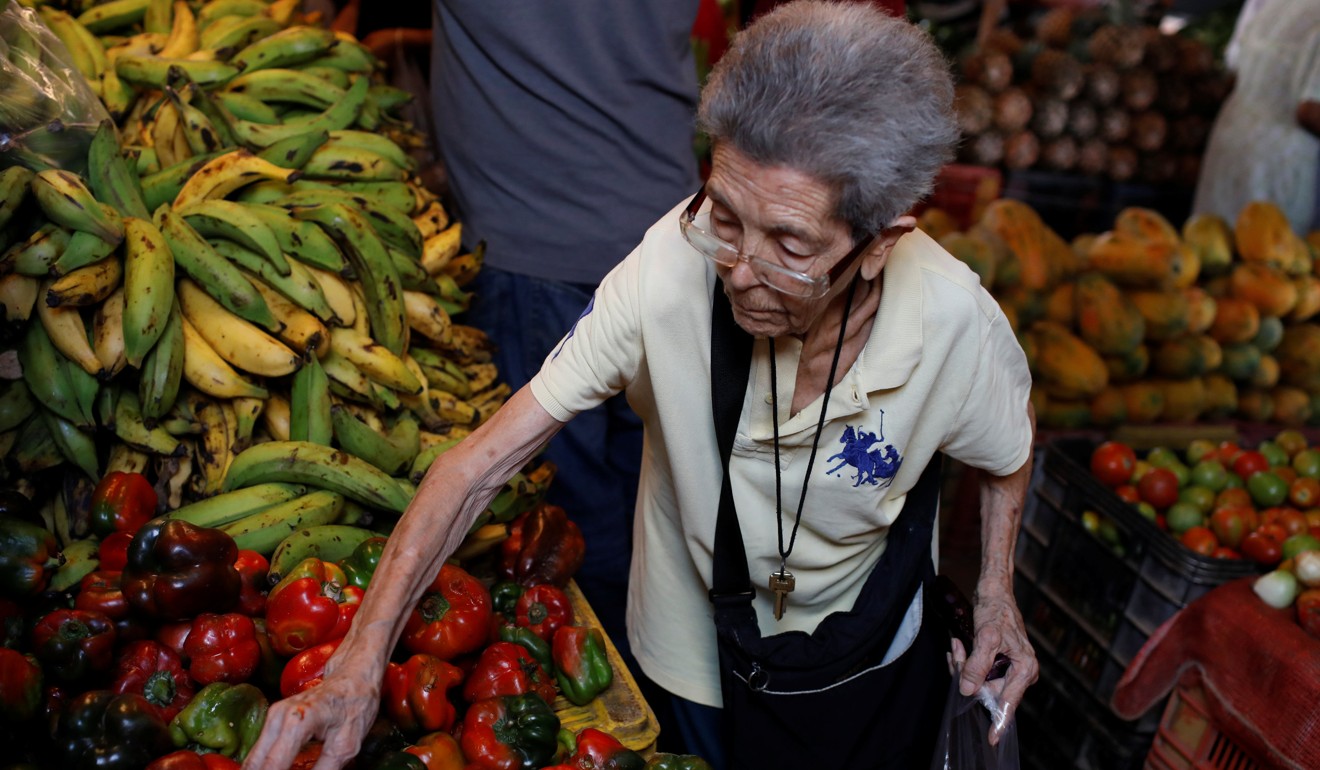 A woman selects peppers at a vegetable street market in Caracas, Venezuela. Photo: Reuters