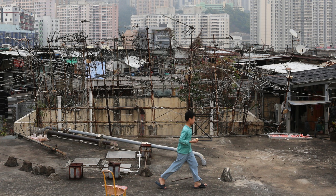 A child walking past cubicle homes constructed on an industrial building rooftop in Kwun Tong. Photo: Dickson Lee